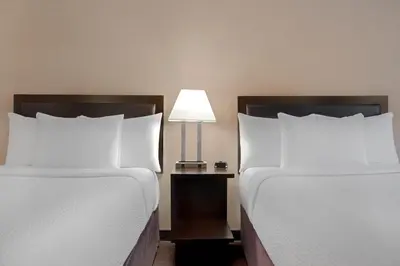 a hotel room with two beds and a lamp at Ramada Plaza by Wyndham Calgary Downtown in Calgary