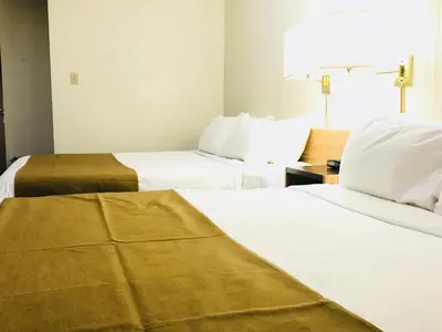 two beds in a hotel room with white sheets at Northern Star Hotel & Convention Center in Slave Lake