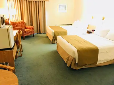 a hotel room with two beds and a chair at Northern Star Hotel & Convention Center in Slave Lake