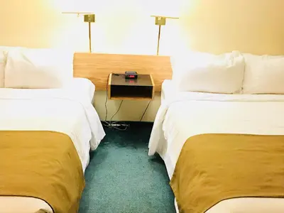 a hotel room with two beds and a table between them at Northern Star Hotel & Convention Center in Slave Lake