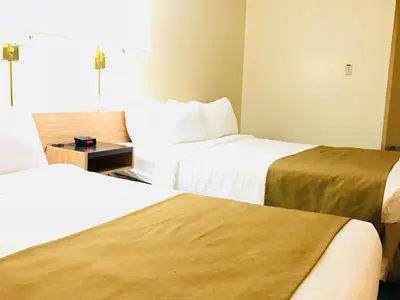 a hotel room with two beds and a table at Northern Star Hotel & Convention Center in Slave Lake