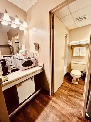 a bathroom with a toilet and a microwave on a counter at Royal Hotel Lloydminster in Lloydminster