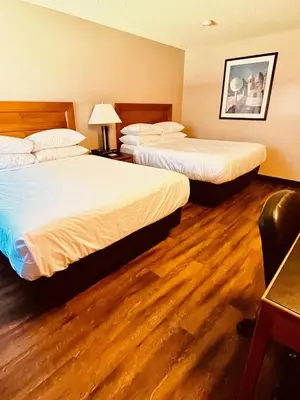 two beds in a hotel room with wood floors at Royal Hotel Lloydminster in Lloydminster