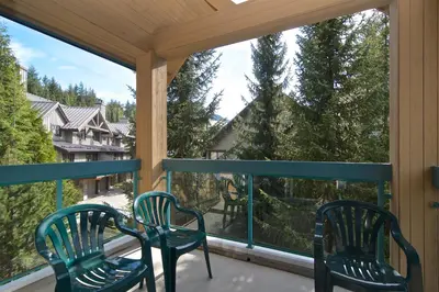 two chairs on a porch with a view of trees at Snowbird by Bill in Whistler