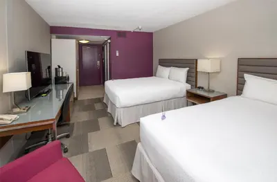 a hotel room with two beds and a desk at Coast Prince George Hotel by APA in Prince George
