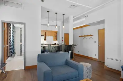 a living room with a blue chair and a kitchen at Savoy Hotel in Nelson