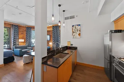 a kitchen with a sink and a living room at Savoy Hotel in Nelson