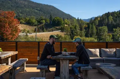 two people sitting at a table on a deck at Savoy Hotel in Nelson