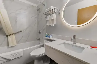 a bathroom with a sink and a toilet and a mirror at SureStay Plus by Best Western Brooks in Brooks