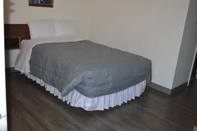 a bed with a gray comforter and pillows at A1 Motel And Campground in Bassano