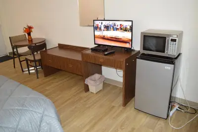 a room with a desk with a television and a microwave at A1 Motel And Campground in Bassano