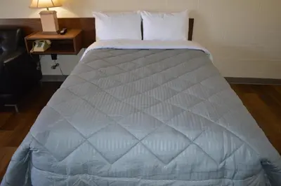 a large bed in a room with a lamp on a table at A1 Motel And Campground in Bassano