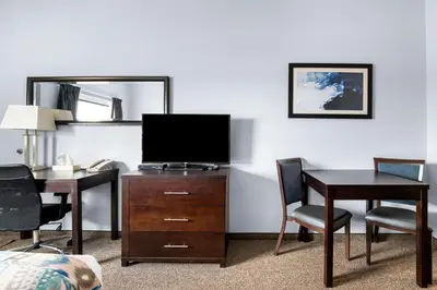 a hotel room with a desk and a television on a dresser at SureStay Studio by Best Western Hardisty in Hardisty