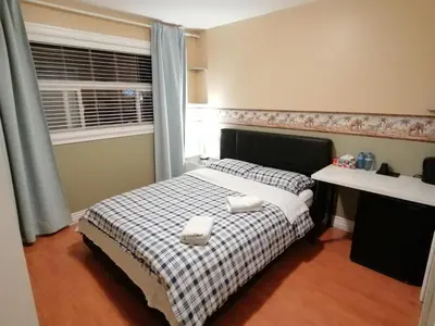 a bedroom with a bed with two towels on it at Three Kittens Guesthouse in Burnaby
