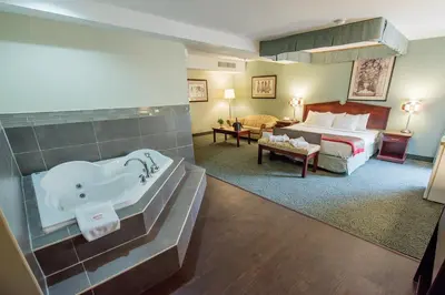 a hotel room with a bath tub and a bed at Harrison Lake Hotel in Harrison Hot Springs