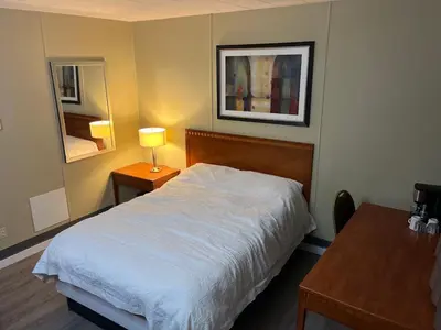 a bedroom with a bed and a table with a lamp at Schell Motel in Vernon