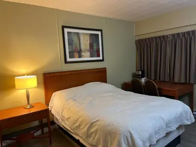 a bedroom with a bed and two desks and a lamp at Schell Motel in Vernon