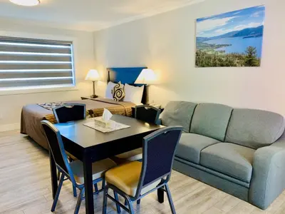 a living room with a couch and a table and a bed at Traveler's Motel Penticton in Penticton