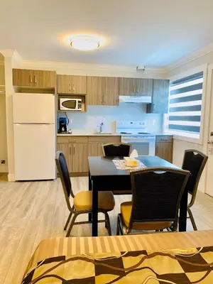 a kitchen with a table and chairs and a refrigerator at Traveler's Motel Penticton in Penticton