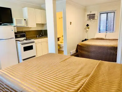 a small room with two beds and a kitchen at Traveler's Motel Penticton in Penticton