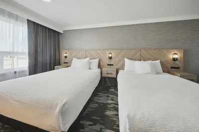two beds in a hotel room with white sheets at Sandman Hotel Red Deer in Red Deer