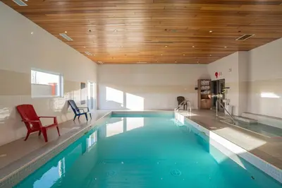 a large swimming pool with a red chair in a room at Sandman Hotel Red Deer in Red Deer