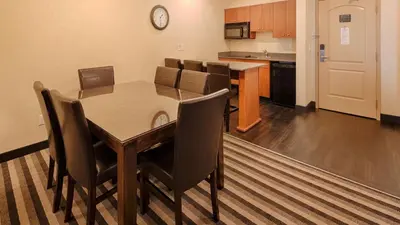 a dining room with a table and chairs and a kitchen at Best Western Plus Meridian in Lloydminster