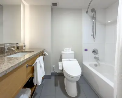 a bathroom with a toilet and a tub and a sink at Coast Chilliwack Hotel by APA in Chilliwack