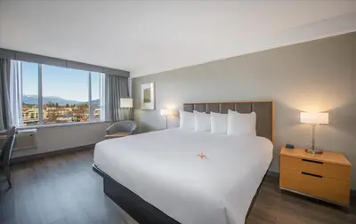 a hotel room with a large bed and a large window at Coast Chilliwack Hotel by APA in Chilliwack