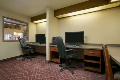 an office with two desks with chairs and a computer monitor at Super 8 by Wyndham Fort Nelson BC in Fort Nelson