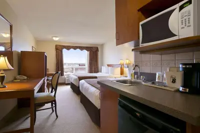 a hotel room with a bed and a kitchen at Super 8 by Wyndham Fort Nelson BC in Fort Nelson