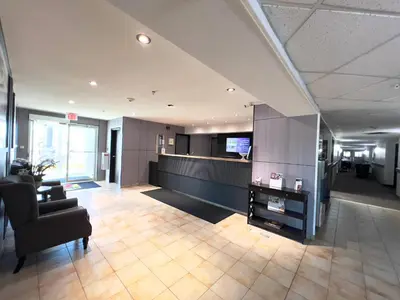 an office lobby with a couch and a television at Super 8 by Wyndham Whitecourt in Whitecourt