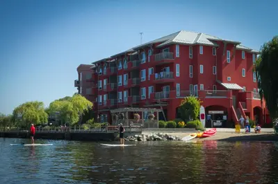 two people on surfboards in the water in front of a red building at Manteo at Eldorado Resort in Kelowna