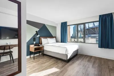 a bedroom with a bed and a desk and a window at Hotel Willo - previously known YWCA Hotel in Vancouver