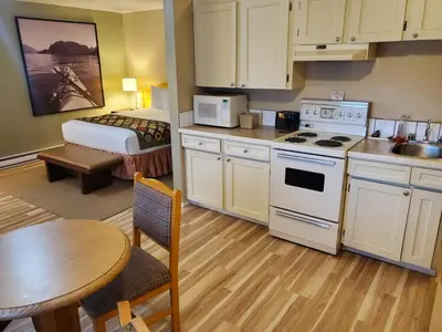 a kitchen with a table and a room with a bed at Super 8 by Wyndham Duncan in Duncan
