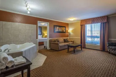 a hotel room with a bath tub and a couch at Super 8 by Wyndham Edmonton International Airport in Leduc
