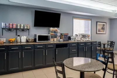 a kitchen with black cabinets and a table with chairs at Super 8 by Wyndham Edmonton International Airport in Leduc