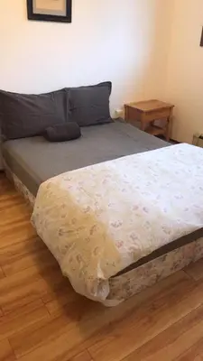 a bed in a bedroom with a wooden floor at Vancouver Backpacker House - 10 min walk to Metrotown skytrain station in Burnaby