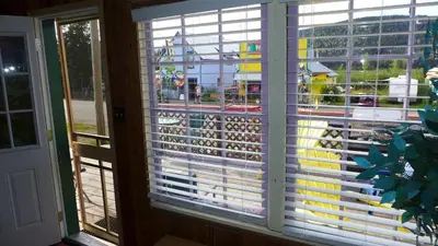 a window with blinds on it with a view of a playground at Mountain Thyme Getaway in Barkerville