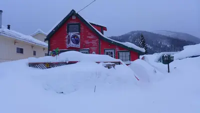 a red house covered in snow in front at Mountain Thyme Getaway in Barkerville