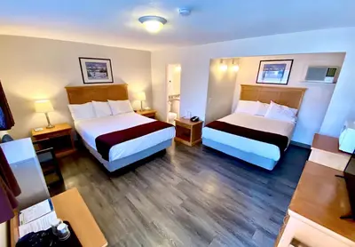 a hotel room with two beds and wooden floors at Silver Star Motel in Vernon