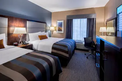 a hotel room with two beds and a desk at Wingate by Wyndham Kamloops in Kamloops
