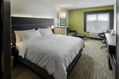 a hotel room with a large bed and a chair at Holiday Inn Express & Suites Kelowna - East by IHG in Kelowna