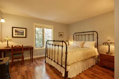 a bedroom with a bed and a desk and a window at Lady MacDonald Country Inn in Canmore