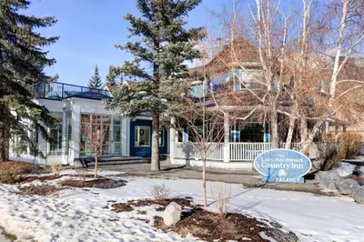 a house with a sign in front of it in the snow at Lady MacDonald Country Inn in Canmore