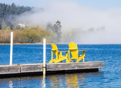 two chairs sitting on a dock on a lake at Birds of a Feather Victoria Oceanfront Studio Suites in Colwood
