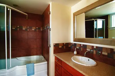 a bathroom with a sink and a shower and a mirror at Birds of a Feather Victoria Oceanfront Studio Suites in Colwood