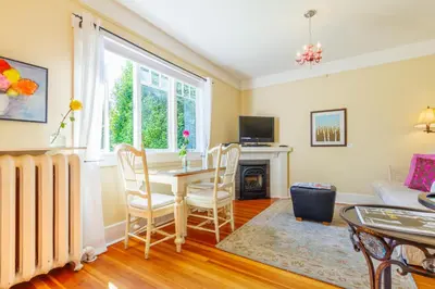 a living room with a table and chairs and a fireplace at Fairholme Manor Inn in Victoria