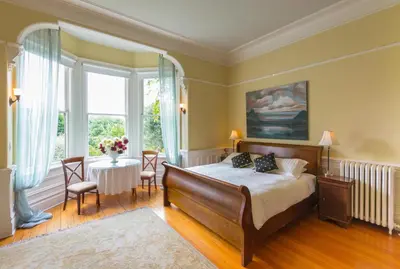 a bedroom with a bed and a table with chairs at Fairholme Manor Inn in Victoria