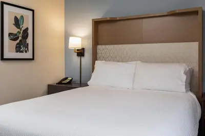a bedroom with a large white bed and a lamp at Holiday Inn Victoria - Elk Lake by IHG in Victoria
